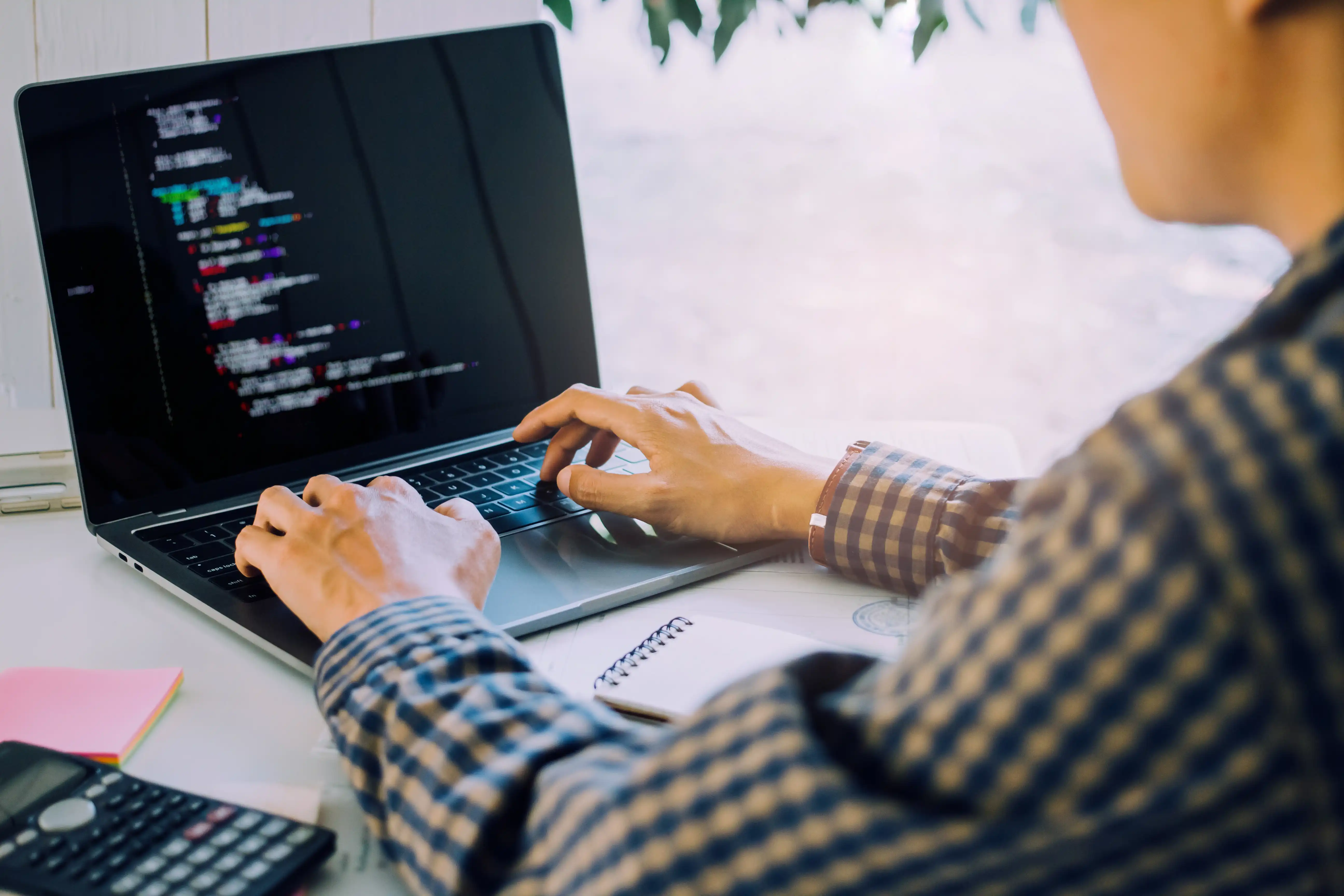 Man typing code into laptop computer.