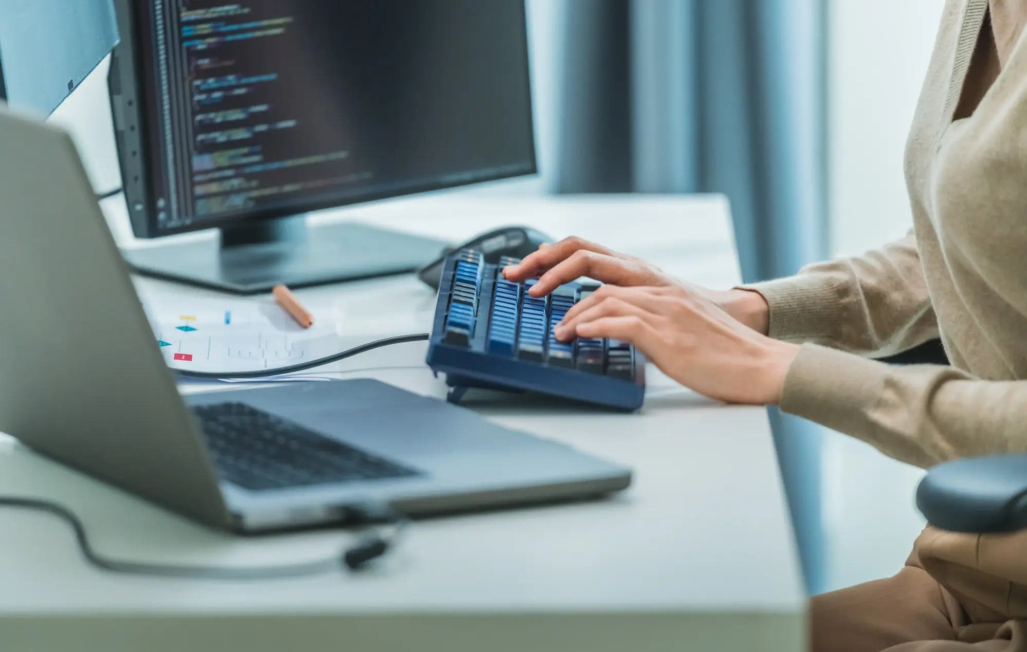 Woman  typing into computer workstation with docked laptop and extra monitors.