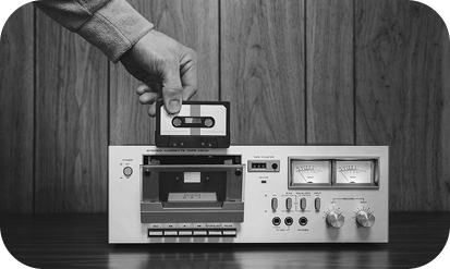 Person inserting a tape into an old cassette player; black and white