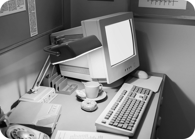 Corner desk with old computer, keyboard, and lamp